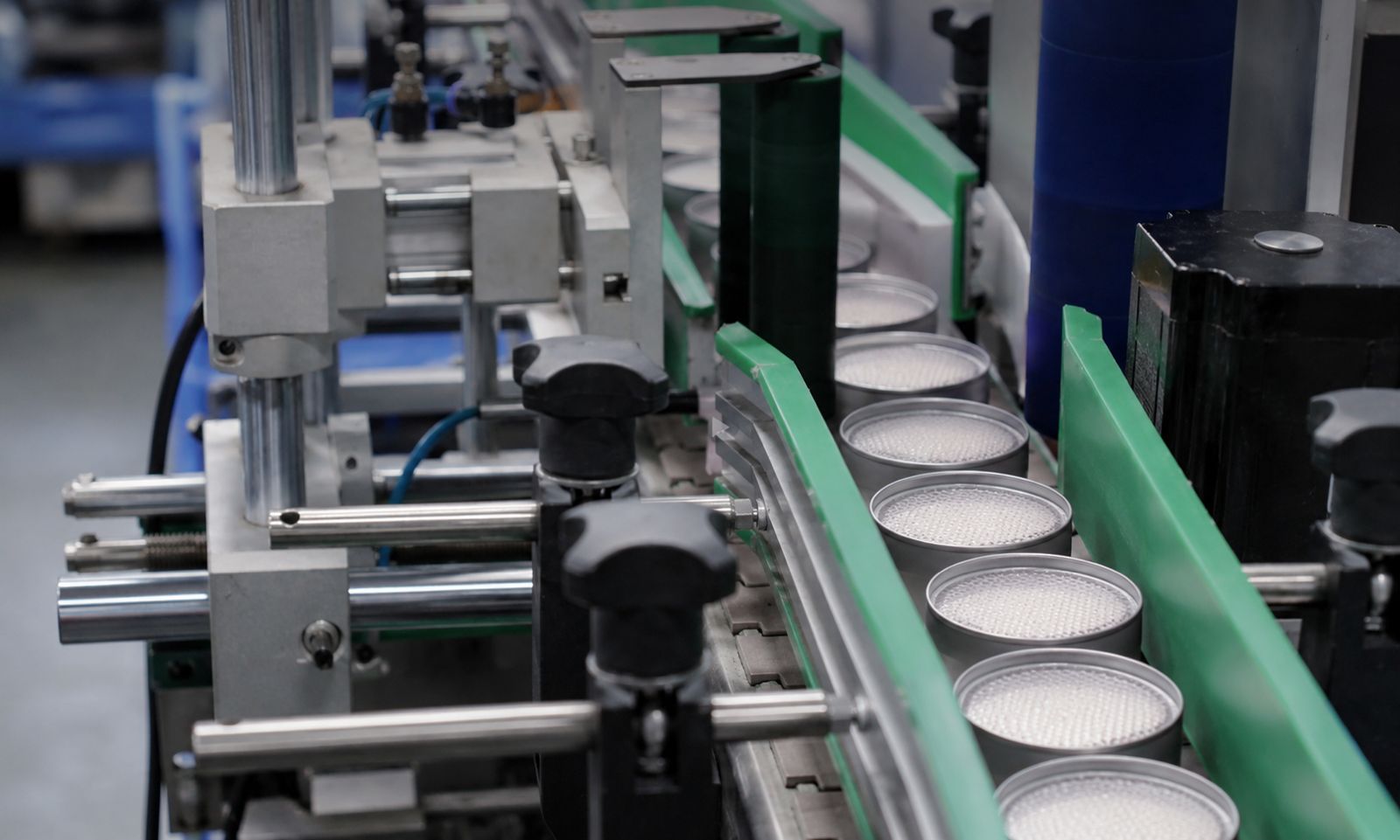 Tins being filled with white scent beads on a production line